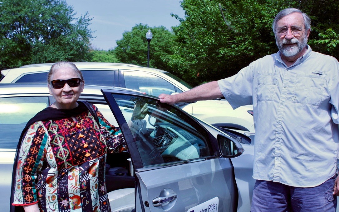 Neighbor Ride passenger and volunteer driver stand outside of car with open passenger-side door