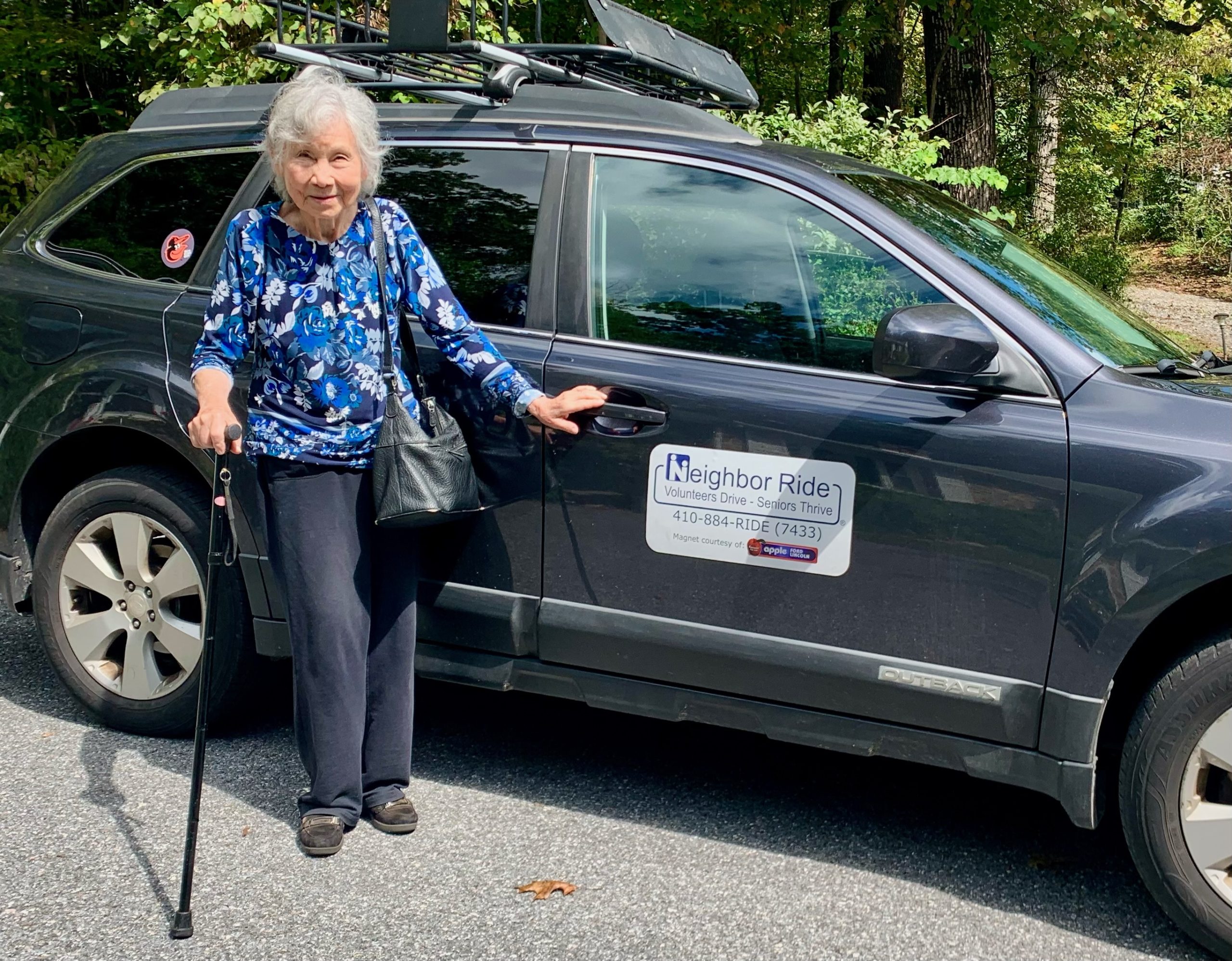 Neighbor Ride Passenger Standing Outside of Vehicle with Neighbor Ride Car Magnet on the door