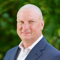Professional headshot of man with blue blazer outside