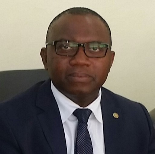 Man sitting posed in a black suit and tie