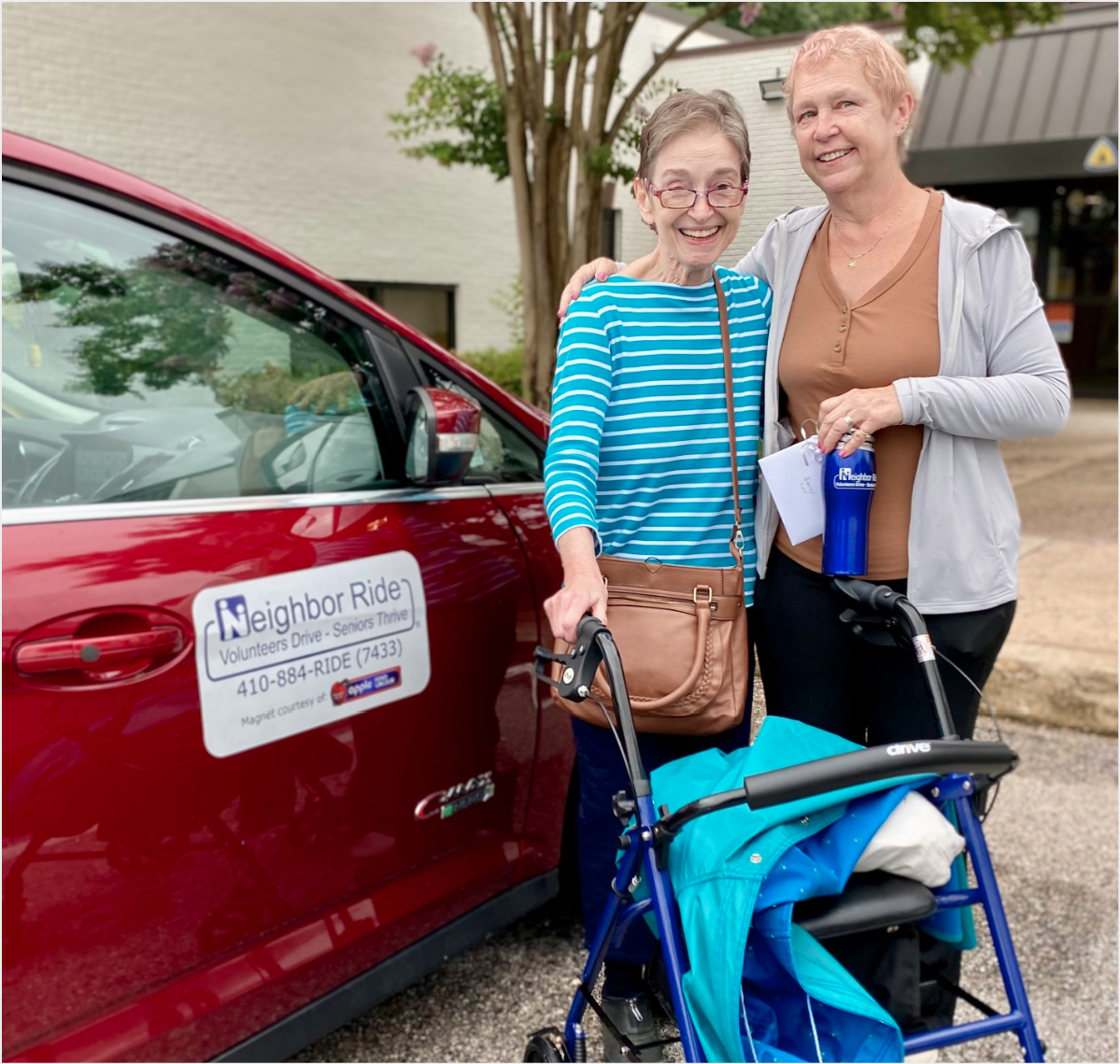 A volunteer posing with a rider next to red car